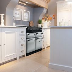 a stove top oven sitting inside of a kitchen next to white cupboards and drawers