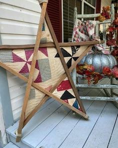 a large wooden star sitting on top of a porch next to a chair and pumpkins