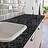 a white sink sitting on top of a counter next to a black countertop with flowers in vases