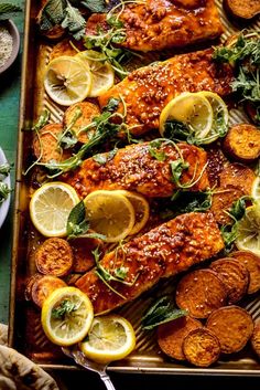 salmon with lemons and herbs on a baking sheet