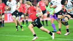 a rugby player runs with the ball in his hand as other players run behind him