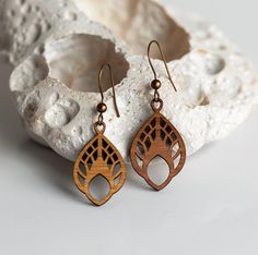 two pairs of wooden earrings sitting on top of a rock