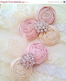 three pink hair clips with diaper flowers on top of white lacy fabric and lace