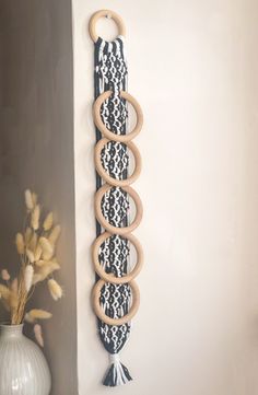 a wall hanging made out of wooden circles and tassels with a vase on the side