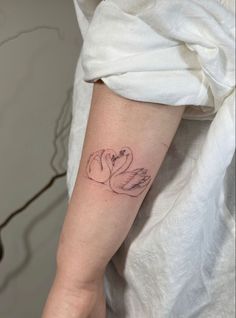 a woman's arm with a tattoo on it that has two swans in the middle