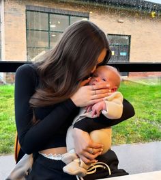 a woman holding a baby in her arms while sitting at a table with an open window