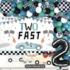 two fast cars are on display in front of balloons and streamers that spell out the number 2