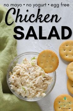 chicken salad in a glass bowl with crackers next to it on a white surface