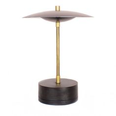 a lamp that is on top of a wooden stand with a metal base and a gold plated light