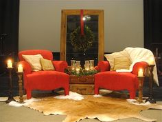 two red chairs sitting next to each other in front of a mirror with candles on it