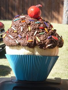 a cupcake with chocolate frosting and sprinkles on top sitting in a blue wrapper