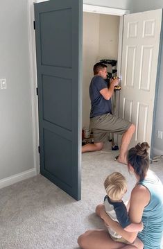 a man and two children sitting on the floor in front of an open door taking pictures