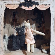 two stuffed animals are standing in front of a stage with curtains on the sides and one is holding a teddy bear