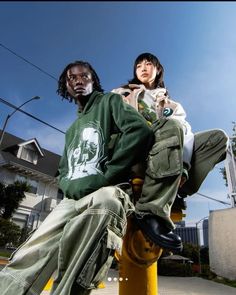 two people sitting on top of a yellow fire hydrant