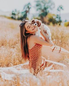 a woman holding a dog in her arms while sitting on a blanket with a basket