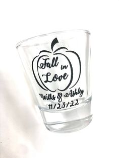 an apple glass with the words fall in love written on it's side, sitting against a white background