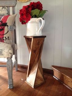 a vase with flowers sitting on top of a wooden table next to a white chair