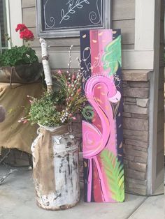 a painting on the side of a house next to a vase with flowers in it