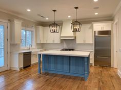 a large kitchen with an island in the middle and two pendant lights hanging from the ceiling