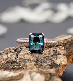 a blue diamond ring sitting on top of a rock