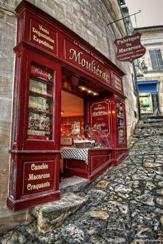 the outside of a store with red doors and windows