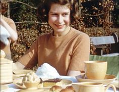 a woman sitting at a table with plates of food and cups of coffee in front of her