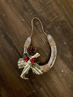 a christmas decoration hanging on the side of a wooden wall with pine cones and berries