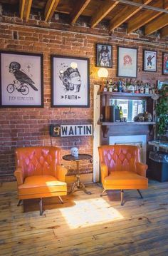 two orange chairs sitting next to each other in front of a wall with pictures on it