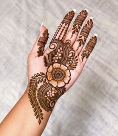 a woman's hand with henna tattoos and flowers on her hands, showing the intricate