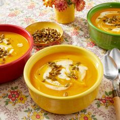 three bowls of soup on a table with spoons