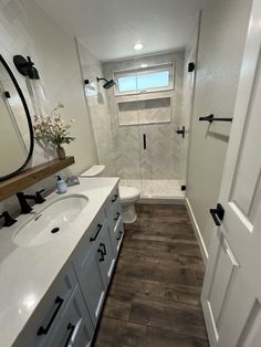 a white bathroom with wood floors and a walk in shower next to the sink area