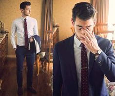 a man in a suit and tie covers his face while standing next to a bed