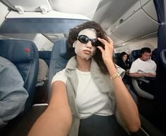 a woman in sunglasses is sitting on an airplane