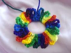 a multicolored crocheted bracelet is hanging on a white cloth with a blue string