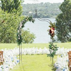 an outdoor ceremony setup with flowers and greenery on the grass, overlooking a body of water