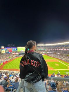 a woman standing on top of a baseball field in front of a stadium filled with people