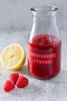 raspberry juice in a glass bottle next to fresh raspberries and lemon