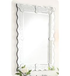 a white mirror sitting on top of a wall next to a vase filled with flowers