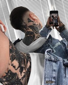 a man with tattoos taking a selfie in front of his mirror while holding a cell phone