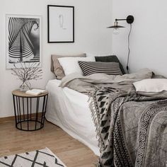 a bedroom with white walls and wood flooring is pictured in this image, there are pictures on the wall above the bed