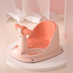 a pink baby seat sitting on top of a white floor next to a curtained window