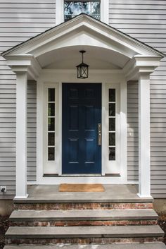 a blue front door on a house with steps leading up to it and a lantern hanging from the roof