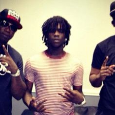 three young men standing next to each other in front of a white wall holding their hands up