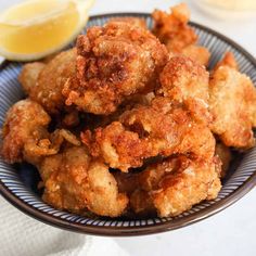 fried food on a plate with lemon wedges