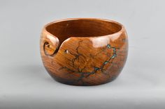 a wooden bowl with blue and brown designs on the inside, sitting on a white surface