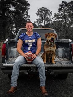 a man sitting in the back of a truck with his dog