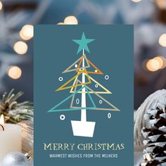 a christmas card with a tree on it next to some candles and other holiday decorations