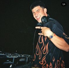 a man with headphones pointing to the side while standing in front of a keyboard