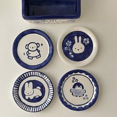 four blue and white plates with animals on them next to a small box that says hello kitty