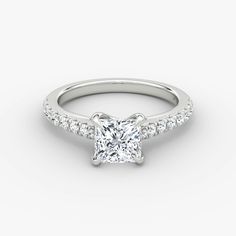 a white gold engagement ring with a princess cut diamond on the side and pave set shoulders